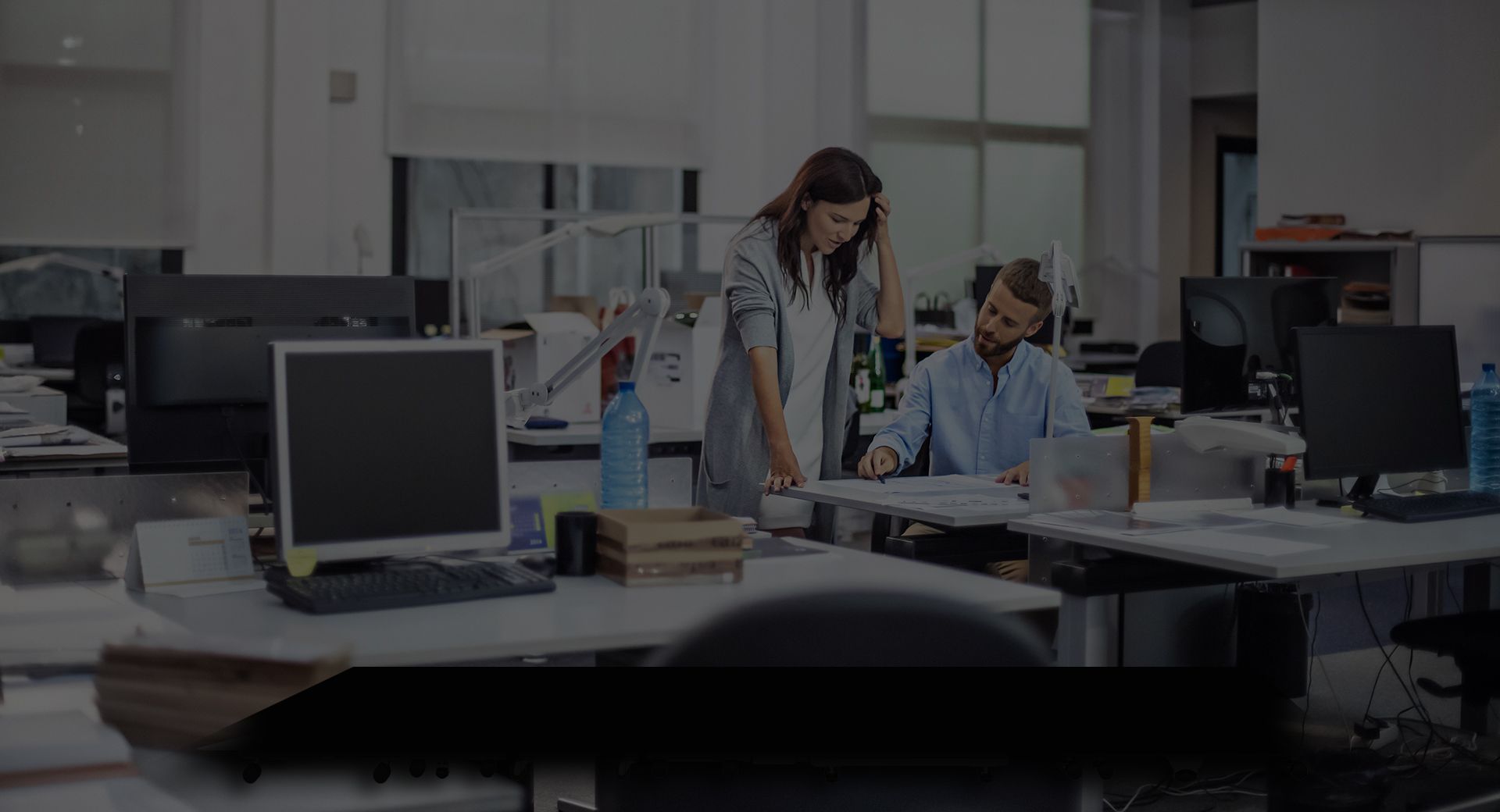 People standing over office full of computers